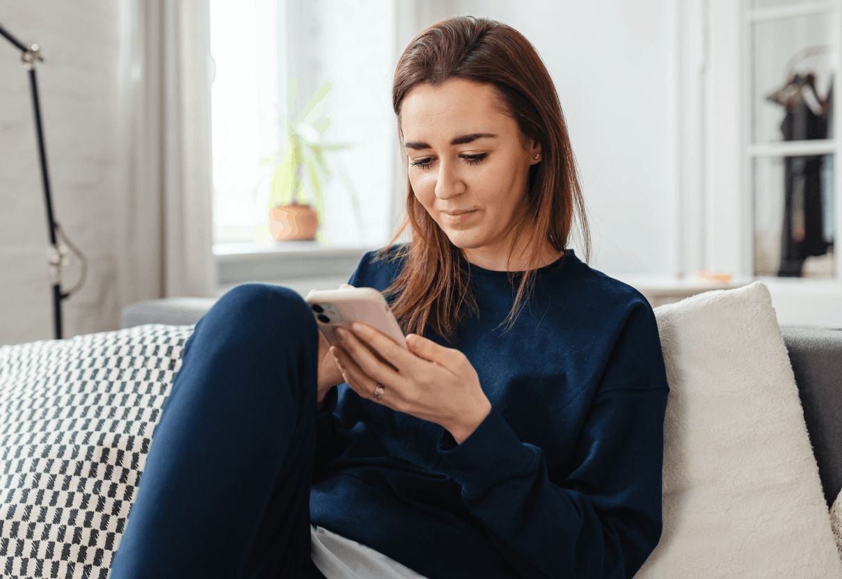 woman sitting on couch holding phone